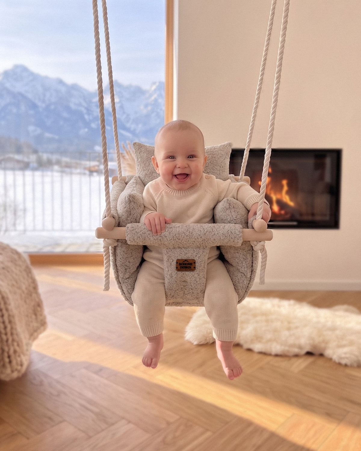 BOHOME Premium Babyschaukel Alpine Champagne – fröhliches Baby in der handgefertigten Schaukel im Wohnzimmer mit Alpenblick